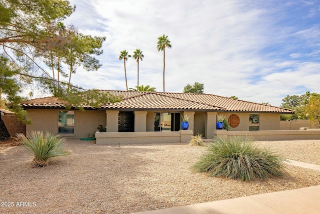 mediterranean / spanish house featuring a tile roof and stucco siding