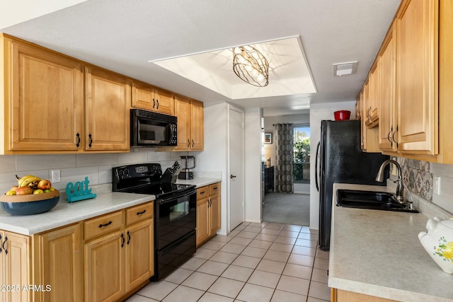 kitchen with light tile patterned floors, tasteful backsplash, light countertops, black appliances, and a sink