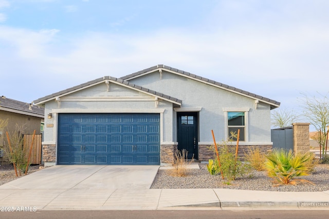 view of front of property featuring an attached garage, stone siding, concrete driveway, a tiled roof, and stucco siding