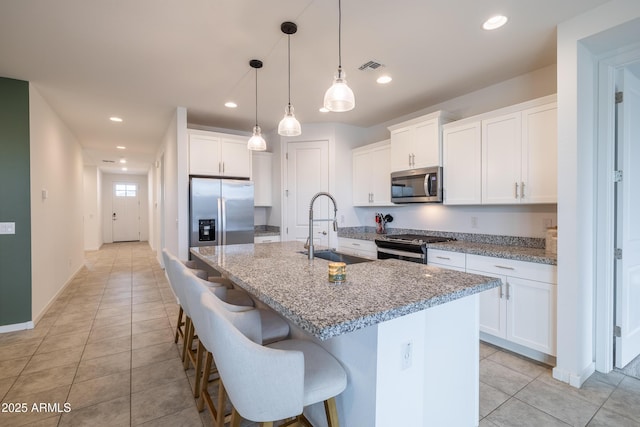 kitchen with a center island with sink, stainless steel appliances, a sink, and recessed lighting