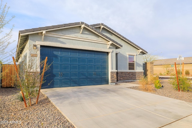 craftsman inspired home with an attached garage, fence, a tile roof, stone siding, and concrete driveway