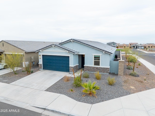 view of front of property with concrete driveway, stone siding, a tile roof, an attached garage, and stucco siding