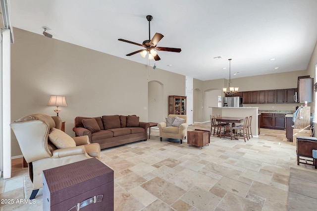 living area with arched walkways, stone tile floors, recessed lighting, baseboards, and ceiling fan with notable chandelier