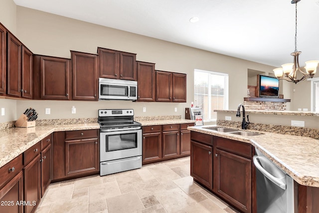 kitchen featuring a notable chandelier, stainless steel appliances, a sink, hanging light fixtures, and stone finish floor