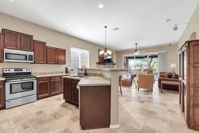 kitchen featuring an island with sink, appliances with stainless steel finishes, open floor plan, and a sink