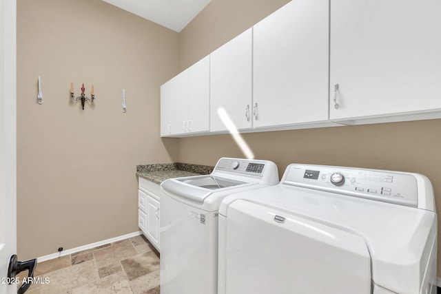 laundry room with washer and dryer, stone finish floor, cabinet space, and baseboards