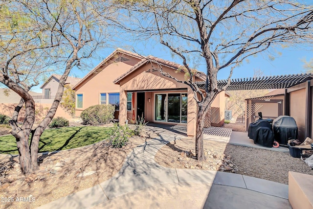 view of front of house with a tiled roof, stucco siding, and a pergola