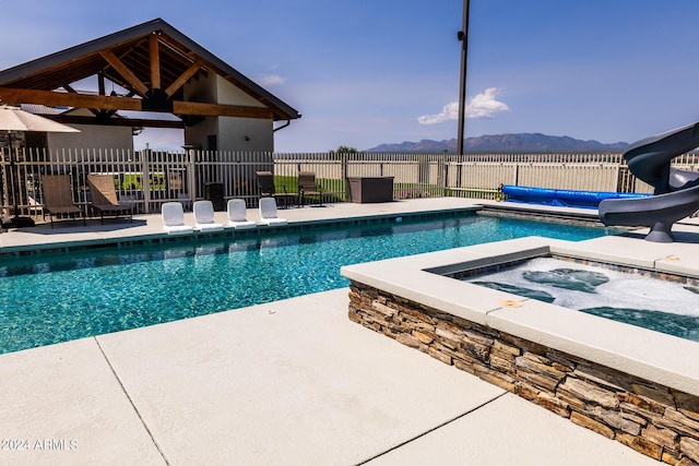 view of pool with an outdoor hot tub, a patio area, a gazebo, a water slide, and a mountain view