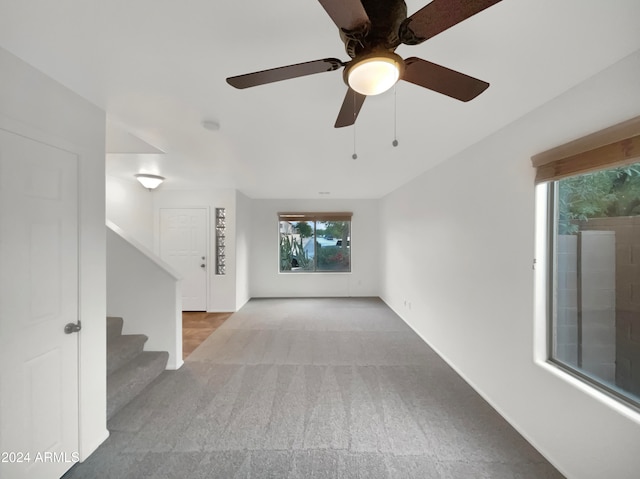 unfurnished living room featuring light carpet and ceiling fan