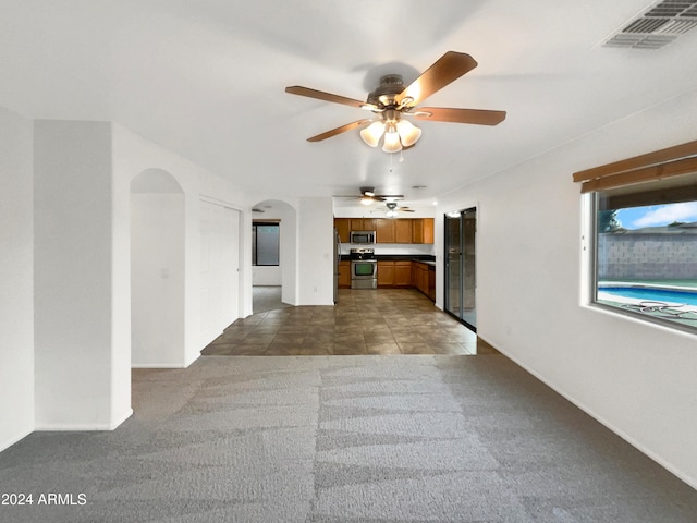 unfurnished living room featuring ceiling fan and carpet