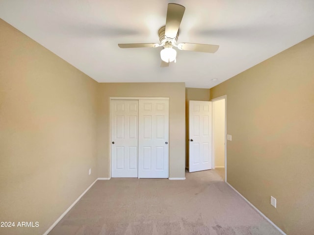 unfurnished bedroom with light carpet, a closet, and ceiling fan