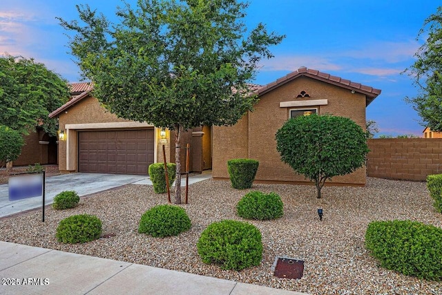view of front facade with fence, stucco siding, concrete driveway, and a tile roof