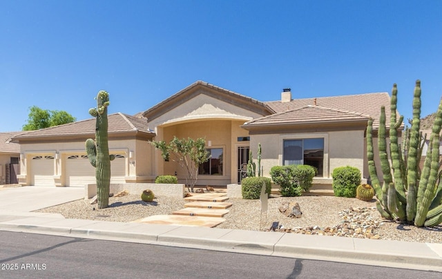 view of front of house featuring a garage, a tile roof, concrete driveway, stucco siding, and a chimney