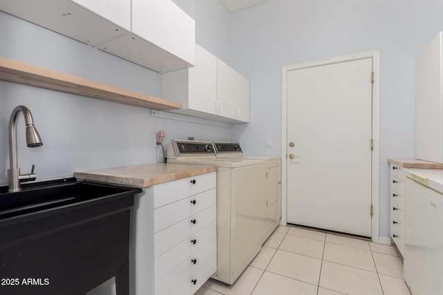 clothes washing area with cabinet space, washer and dryer, and light tile patterned flooring