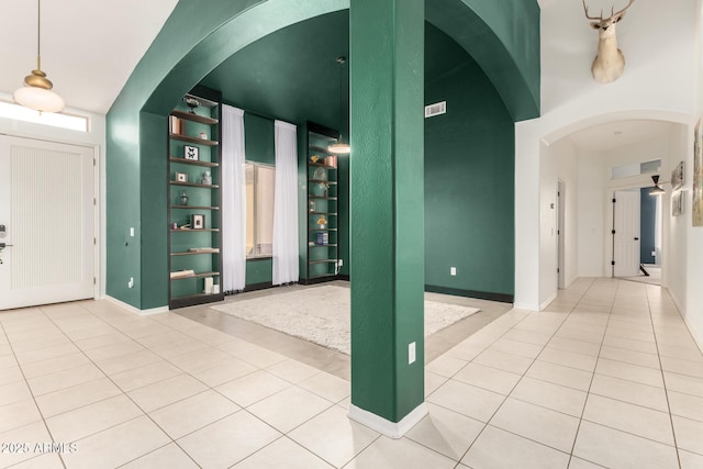 interior space featuring arched walkways, light tile patterned floors, and baseboards