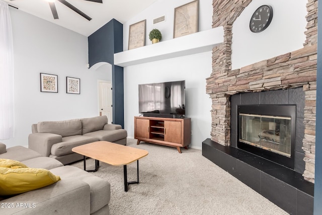 living area with high vaulted ceiling, carpet, ceiling fan, and a stone fireplace