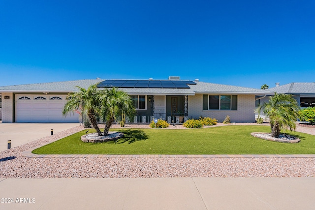 ranch-style house featuring a garage, a front lawn, and solar panels