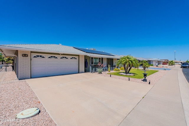 single story home featuring a garage and solar panels