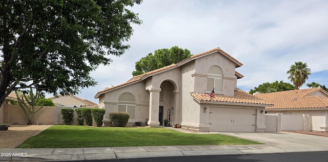 mediterranean / spanish house featuring a front yard, driveway, a tiled roof, and fence