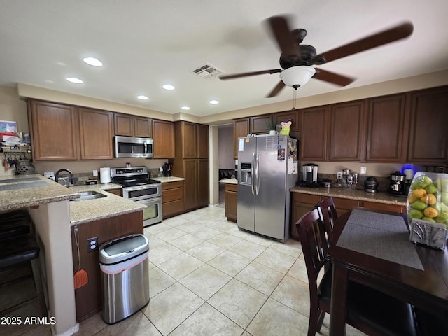 kitchen with a peninsula, a ceiling fan, visible vents, a sink, and stainless steel appliances