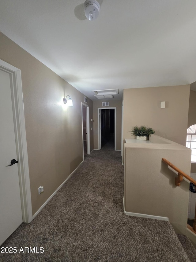 hallway with an upstairs landing, visible vents, and carpet floors