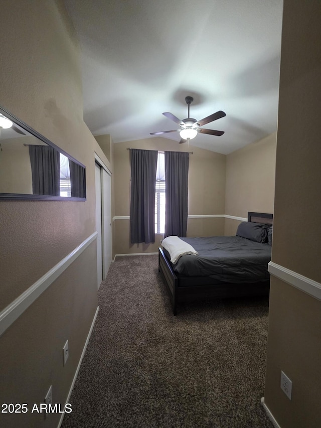 bedroom featuring a closet, a ceiling fan, carpet flooring, lofted ceiling, and baseboards