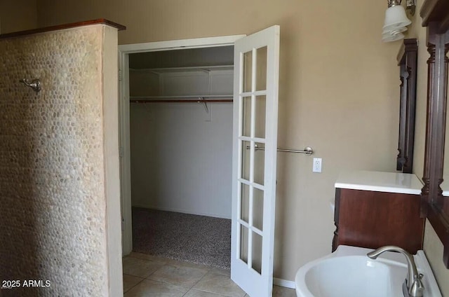bathroom featuring a sink, french doors, a spacious closet, and tile patterned flooring