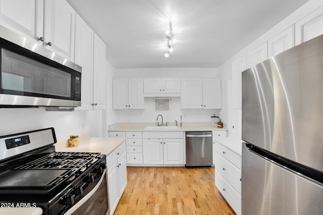 kitchen with sink, white cabinets, light wood-type flooring, and appliances with stainless steel finishes