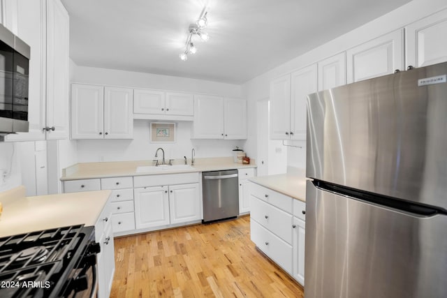 kitchen with sink, white cabinets, light wood-type flooring, and appliances with stainless steel finishes