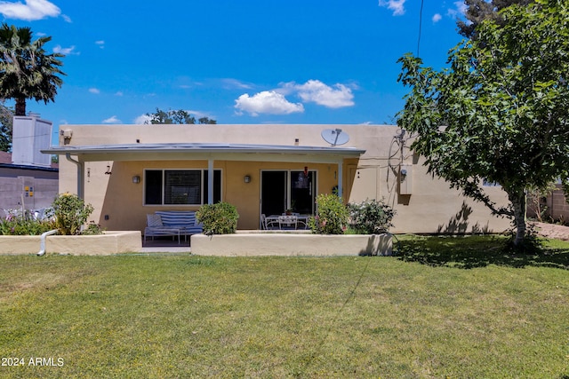 rear view of property with a patio and a lawn