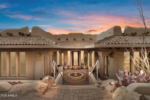 back of property at dusk with a tile roof