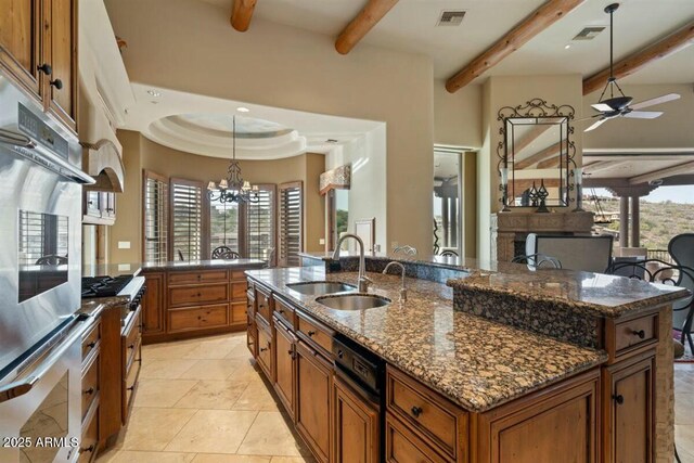 kitchen featuring pendant lighting, brown cabinets, a sink, and visible vents