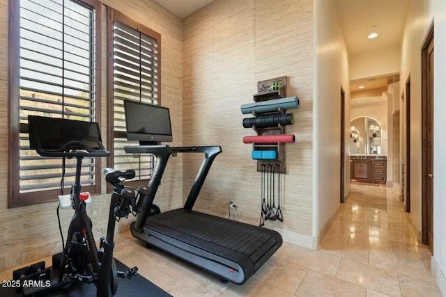 workout area featuring tile patterned flooring, a high ceiling, and baseboards