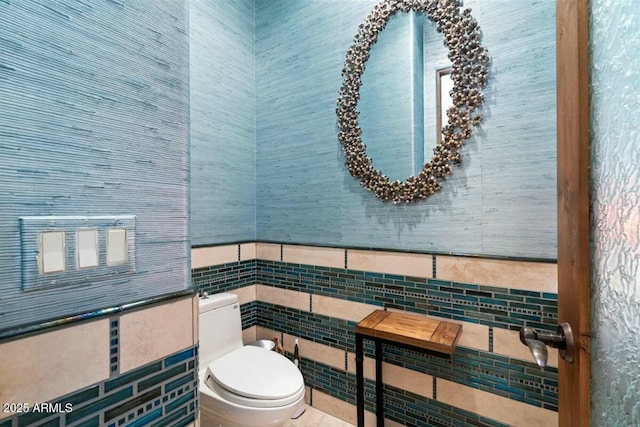 half bathroom featuring toilet and tile walls