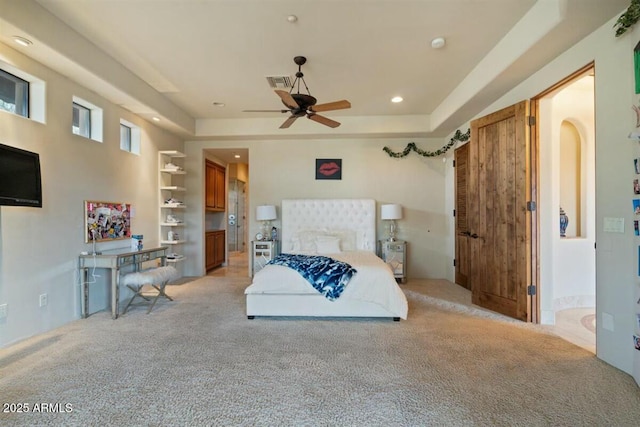 bedroom with arched walkways, recessed lighting, light colored carpet, visible vents, and a raised ceiling