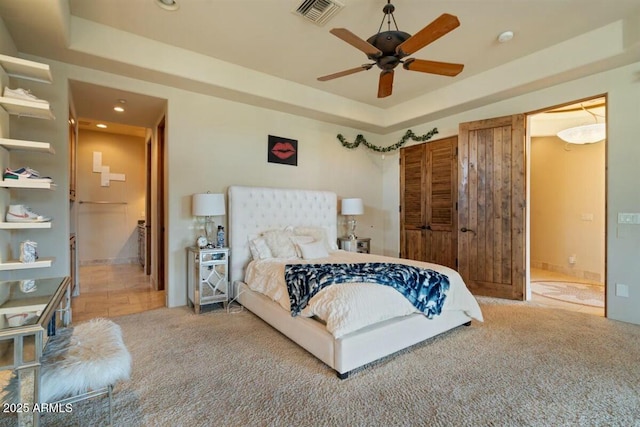 carpeted bedroom with a tray ceiling, recessed lighting, visible vents, and a ceiling fan