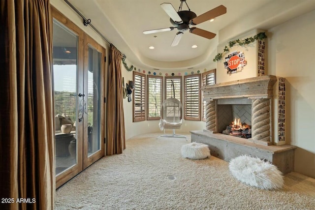 living area with carpet floors, french doors, recessed lighting, a ceiling fan, and a lit fireplace