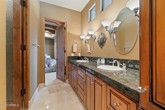 bathroom featuring baseboards, a sink, ensuite bathroom, and double vanity