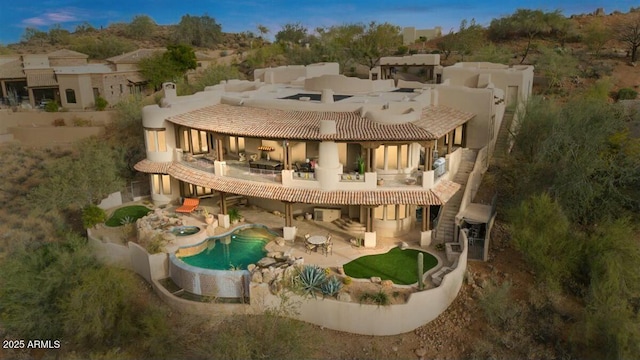 rear view of house with a patio, a balcony, and an outdoor pool