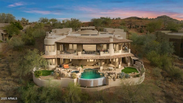 rear view of property featuring a patio, central AC, a balcony, an outdoor pool, and a tiled roof