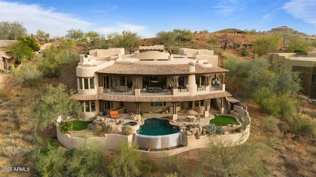 rear view of house with a patio area, a balcony, and an outdoor pool