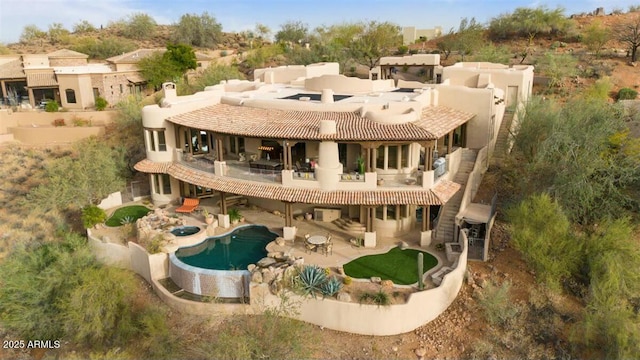 back of property with a patio area, a balcony, and an outdoor pool