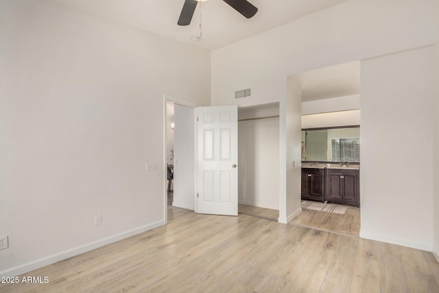 unfurnished bedroom with light wood-type flooring, ensuite bathroom, baseboards, and ceiling fan