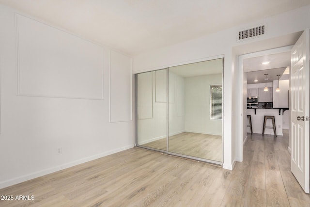 unfurnished bedroom with light wood finished floors, a closet, and baseboards