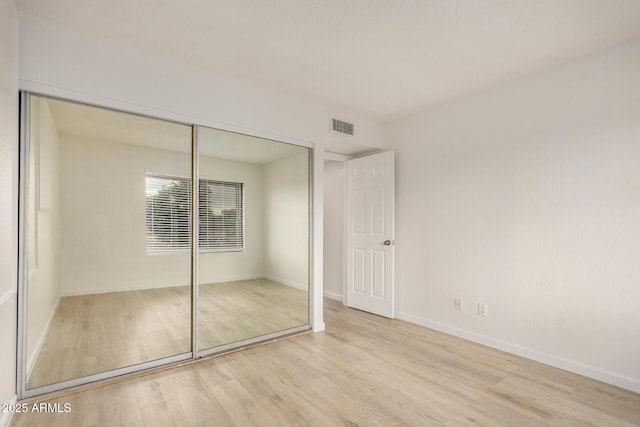 unfurnished bedroom with wood finished floors, a closet, and baseboards
