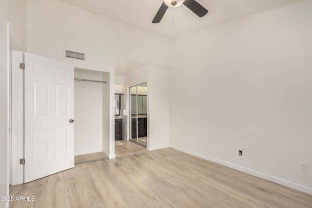 unfurnished bedroom featuring light wood-type flooring, baseboards, ensuite bathroom, and a ceiling fan