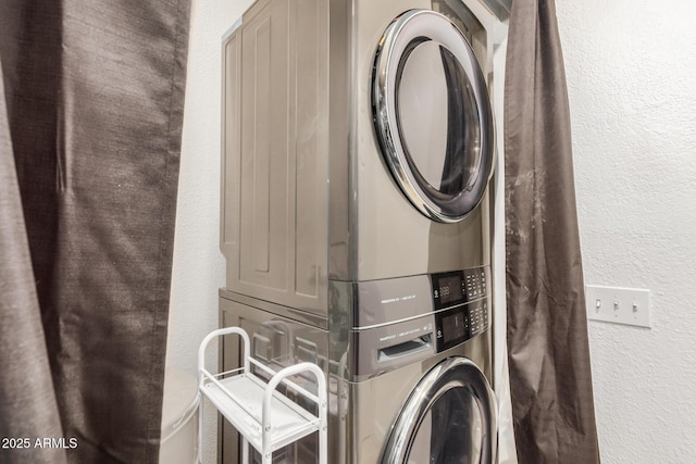 washroom with estacked washer and dryer and a textured wall