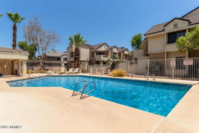 community pool featuring fence, a patio, and a residential view