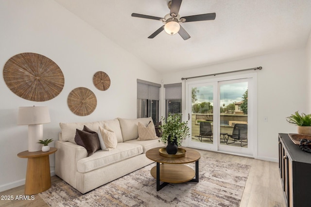 living room with lofted ceiling, light wood-style floors, ceiling fan, and baseboards