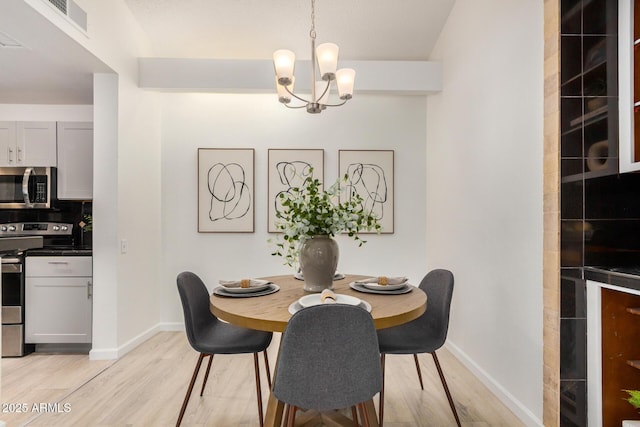dining space with a chandelier, light wood-style flooring, and baseboards